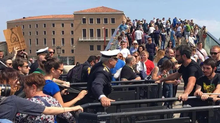 Un gruppo di appartenenti al Centro sociale Morion protesta davanti ad uno dei due varchi, ai piedi del Ponte di Calatrava a piazzale Roma, voluti dal comune per limitare gli ingressi ai turisti a Venezia, 29 aprile 2018. .ANSA