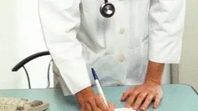 Un medico di base compila una ricetta davanti al computer