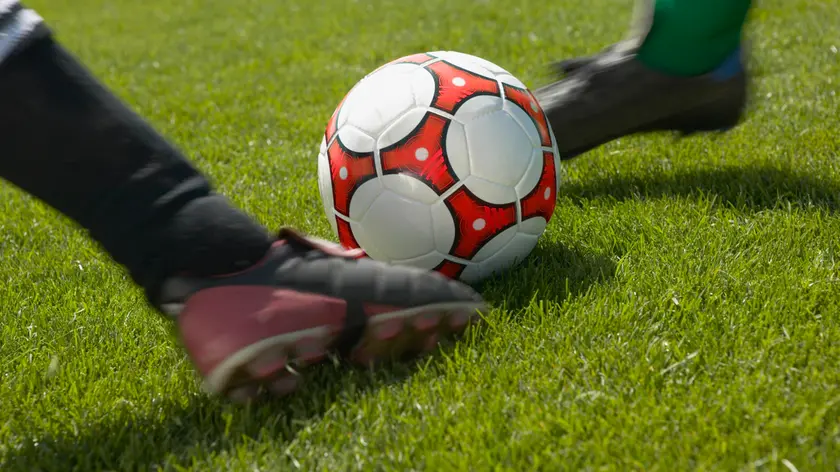 Soccer players kicking the ball simultaneously
