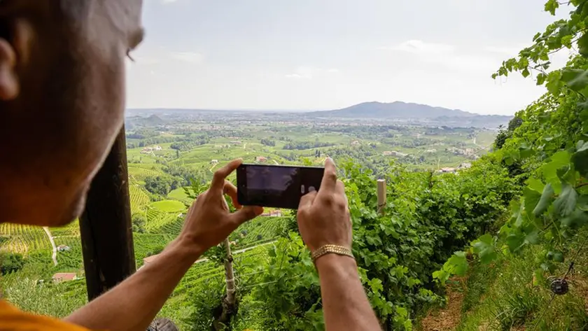 Un turista a fotografa il panorama delle colline Unesco di Conegliano e Valdobbiadene