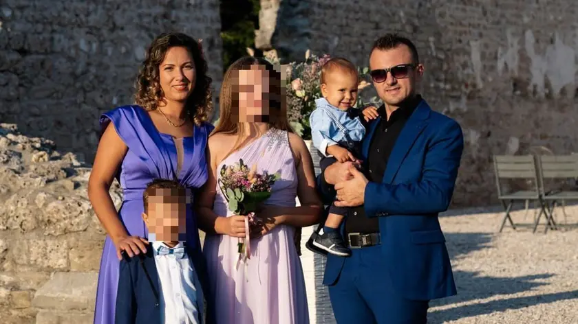Il piccolo Iustin Valentin in braccio a papà con mamma fratelli il giorno del battesimo