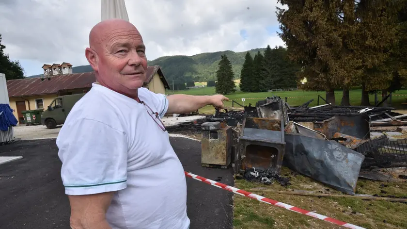 Il gestore mostra ciò che resta del chiosco dei panini sul Cansiglio dopo l'incendio