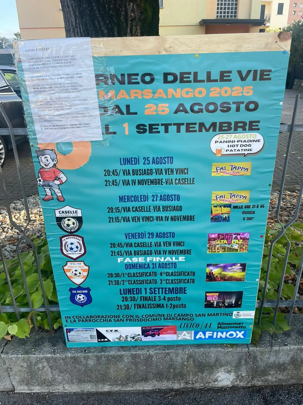 Un cartellone della sagra di paese con attaccata una poesia