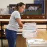 Una volontaria sistema una pila di testi scolastici degli istituti superiori