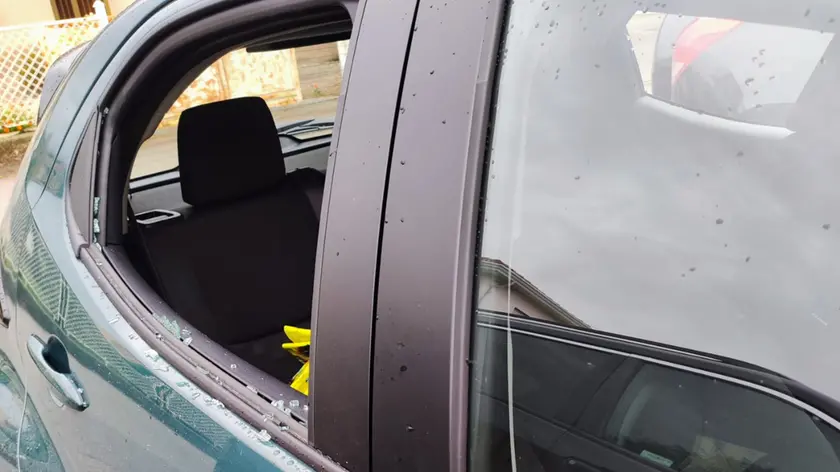 Un'auto con il finestrino distrutto dopo il blitz dei ladri