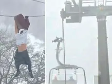 Nel fermo immagine trasmesso da Telefriuli il 32enne aggrappato ai cavi della seggiovia