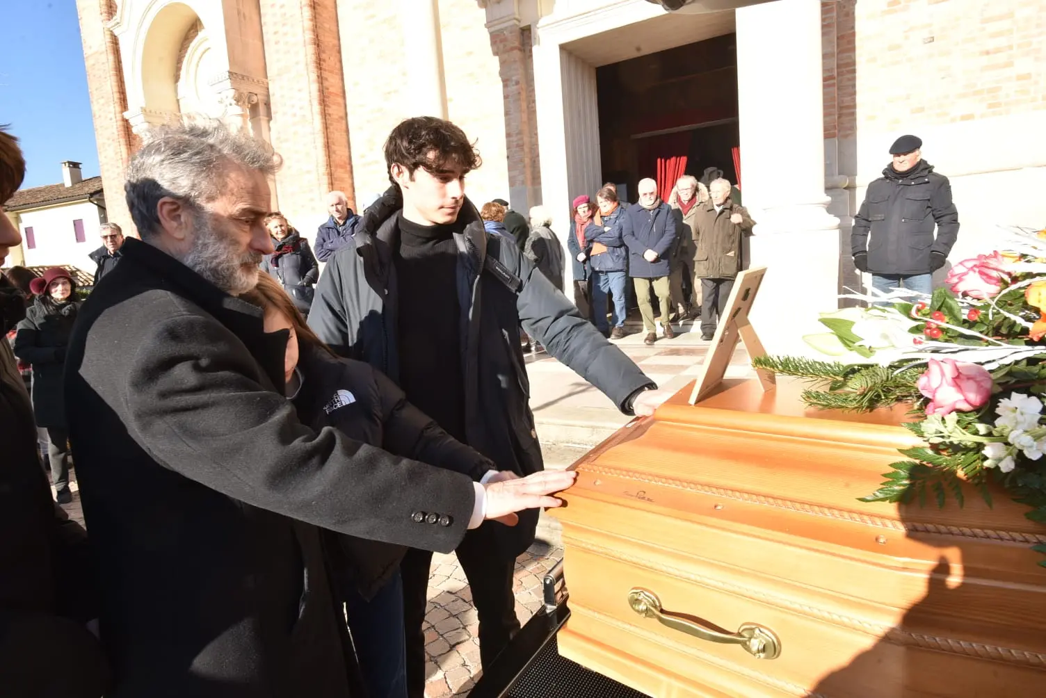 Figlio e nipote accarezzano il feretro