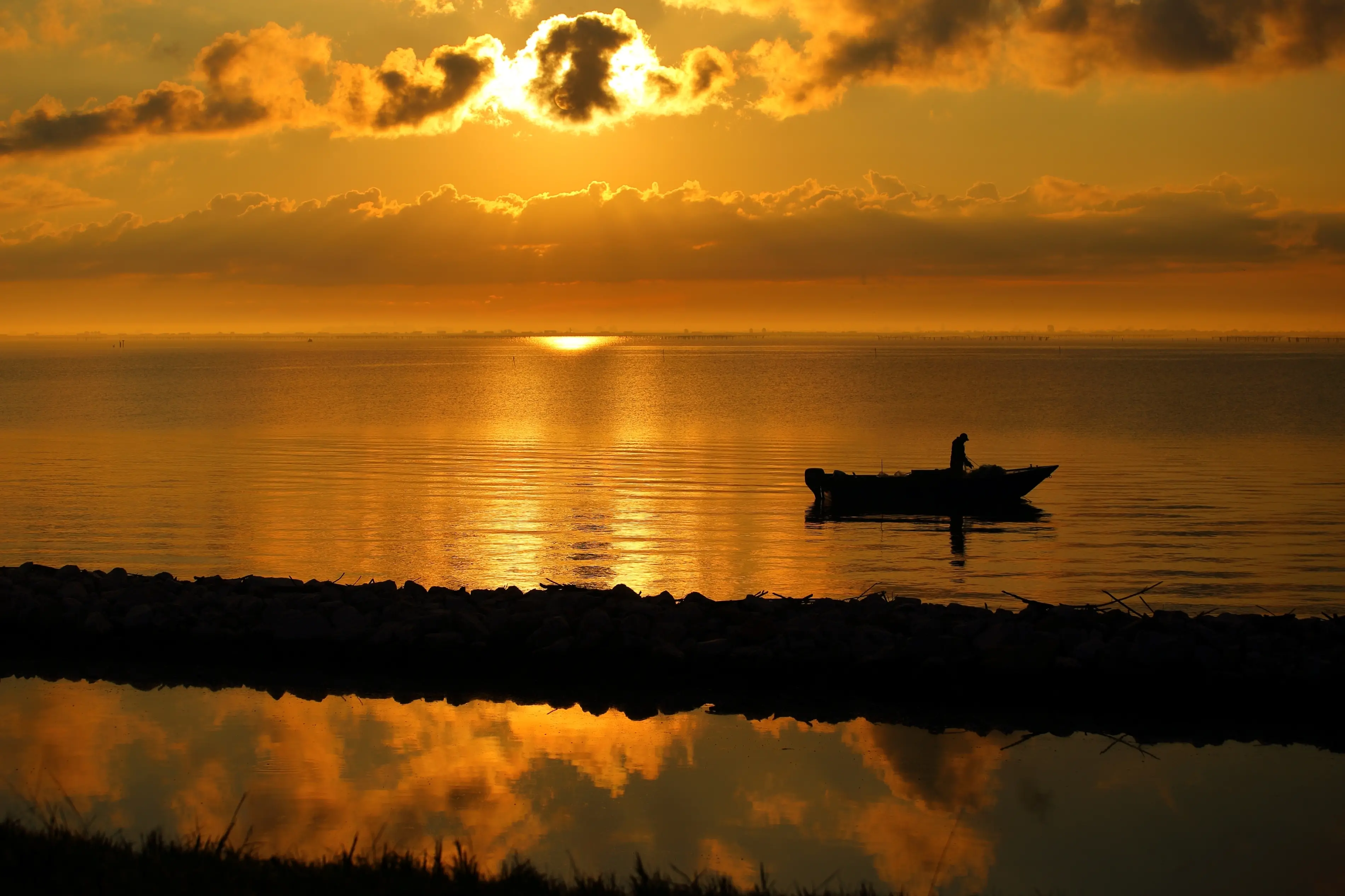 Pescatore al lavoro in un'alba dorata nella sacca di Scardovari., Luigino Zangobbo