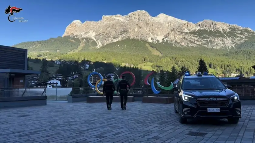 Una pattuglia dell’Arma davanti ai simboli dei Giochi esposti a Cortina