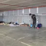 Un migrante si occupa della pulizia della zona dei giacigli al Dal Negro