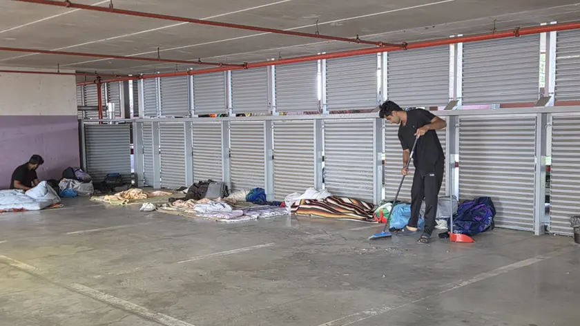 Un migrante si occupa della pulizia della zona dei giacigli al Dal Negro