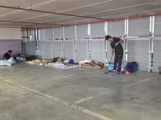 Un migrante si occupa della pulizia della zona dei giacigli al Dal Negro