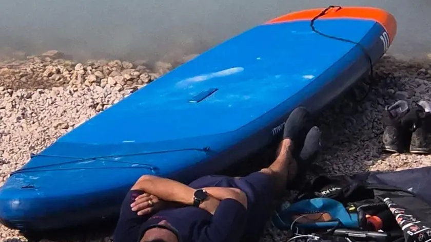 Il turista sdraiato in riva al lago dopo aver solcato le acque con il sup