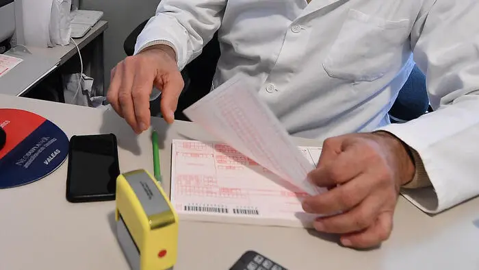 Un medico di base compila una ricetta nel suo studio