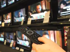 Un utente con il telecomando davanti ai televisori