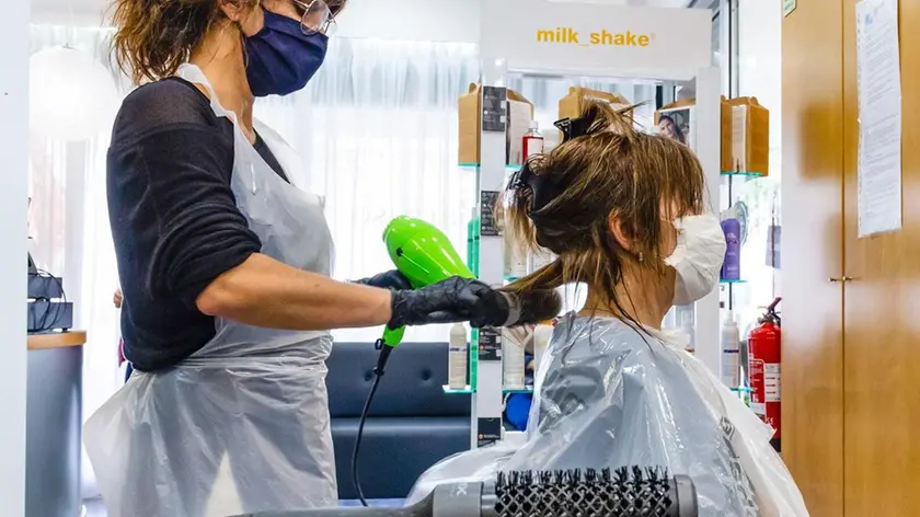 04/05/2020 Porto, una parrucchiera asciuga i capelli di una cliente indossando mascherina e scudo facciale come misura preventiva