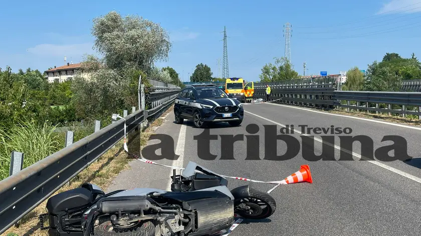Lo scooter ancora a terra e in lontananza il cadavere