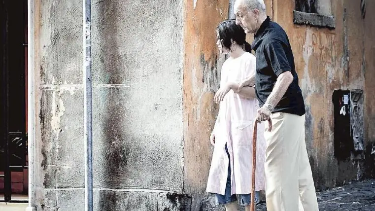 Una badante accompagna un anziano a passeggio in città: l’assistenza è sempre più un peso economico insostenibile per molte famiglie