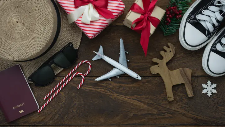 Table top view of Merry Christmas decorations & Happy new year 2019 ornaments concept.Flat lay essential difference objects to travel text & gift box with clothing on modern wooden brown background.