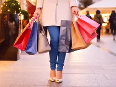 Young woman shopping in the city, legs and hands close up, carrying paper bags.
