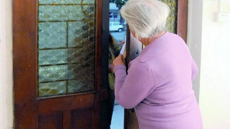 Un anziana che apre la porta a uno sconosciuto