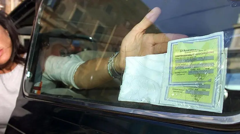 In una foto d'archivio del 1/o agosto 2000, una donna colloca la cedola dell'assicurazione sul vetro posteriore della sua auto. Il premio medio dell'assicurazione rc auto in Italia è in diminuzione: in 5 anni si è ridotto dell'11,8%. Lo sostiene l'Ania, nel rapporto presentato oggi all'assemblea annuale. E si tratta di un trend decrescente: -1,5% nel 2005, -0,8% nel 2006, -2,7% nel 2007 fino ad arrivare a -3,9% nel 2009.ANSA/MONTEFORTE/IAN