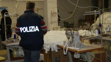 Un agente di polizia all’interno del laboratorio tessile cinese a Camalò